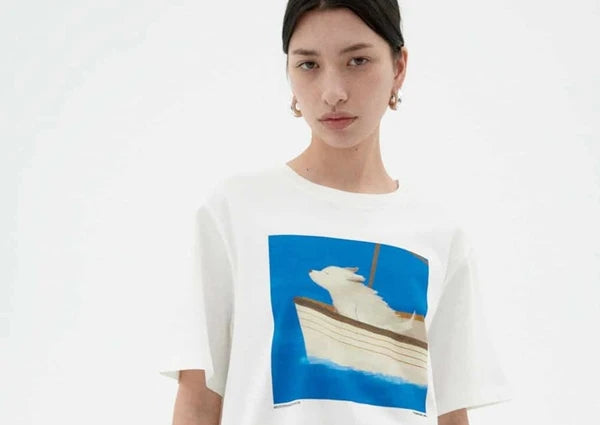 frau mit einem blau weißen T-shirt, motiv: ein Hund auf einem Segelboot streckt seine schnauze in den wind